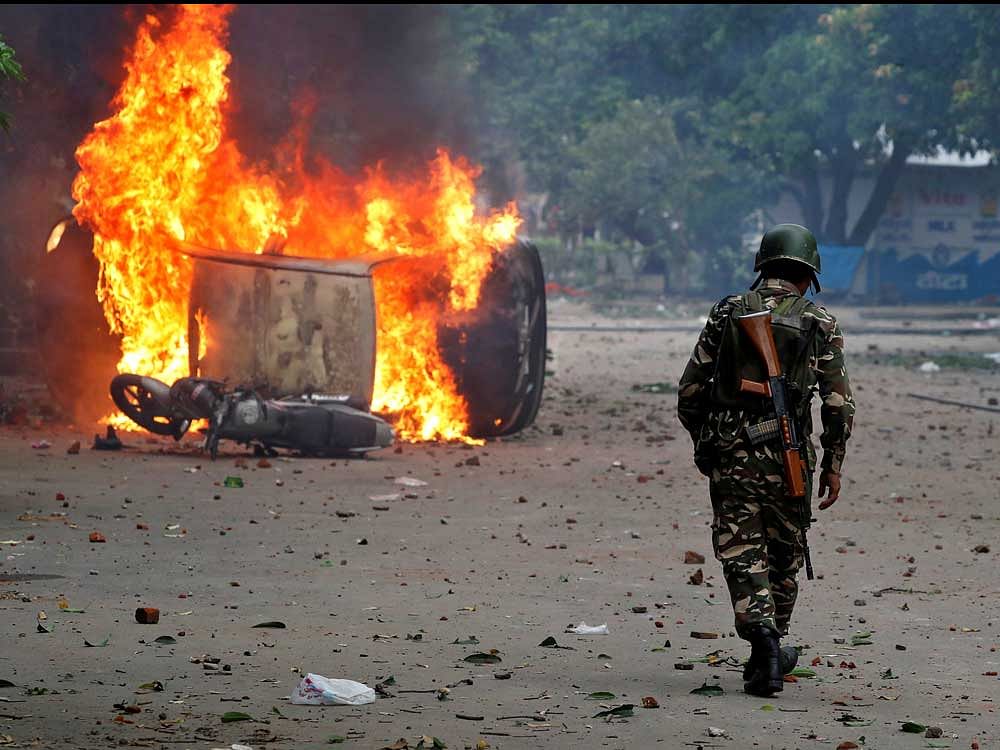 A member of the security forces walks towards a burning vehicles during violence in Panchkula, India, August 25, 2017. REUTERS