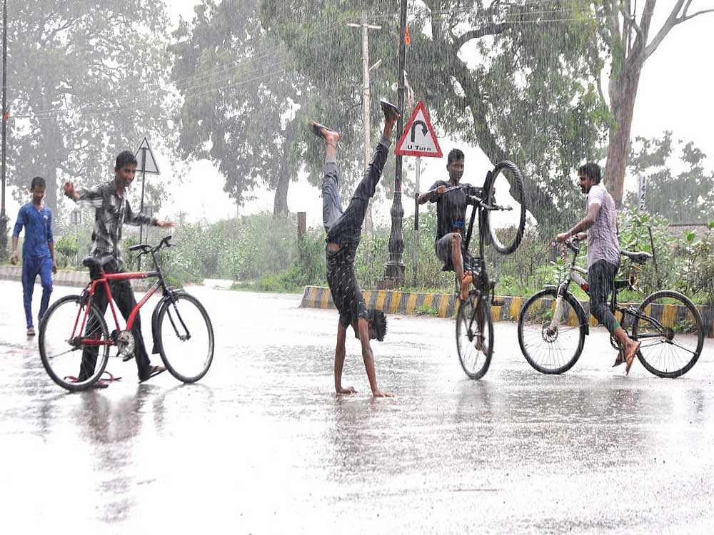 Children try various tricks on a rain-washed road in Hosapete taluk, Ballari district, on Sunday. dh photo
