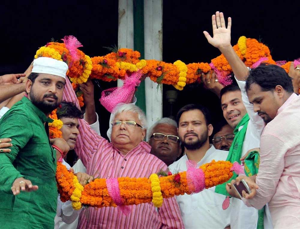 RJD Chief Lalu Prasad with Leader of Opposition in Bihar Assembly Tejashwi Yadav being garlanded by the supporters during a rally against Sirjan Scam in Bhagalpur district on Sunday. PTI Photo