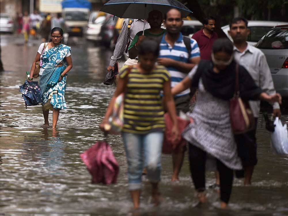 People wade through a water logged street after heavy rain in Mumbai on Wednesday. PTI Photo