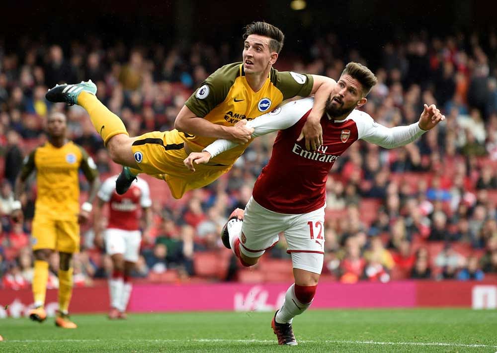 High octane: Brighton's Lewis Dunk leaps in the air to receive the ball even as Olivier Giroud attempts to stop him. Reuters