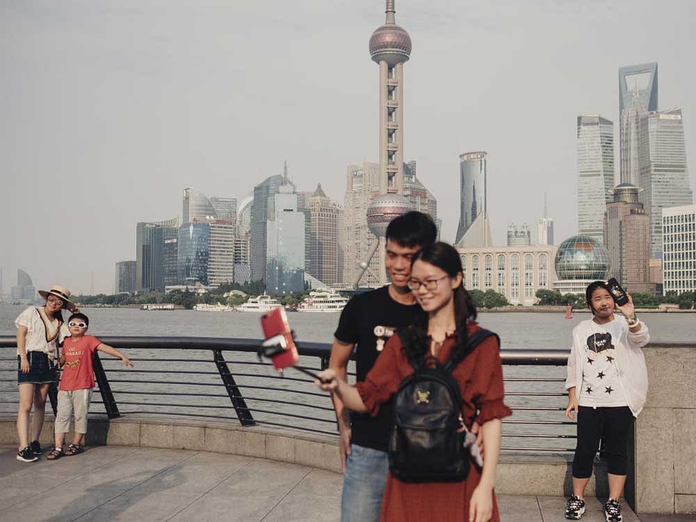 Visitors take selfie photos at a scenic spot in the Bund, a waterfront area in Shanghai, China. The New York Times Photo
