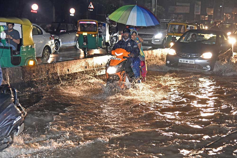 Motorists struggle to negotiate the waterlogged road at Basaveshwara Circle (Chalukya Circle) on Friday. DH Photo/S K Dinesh