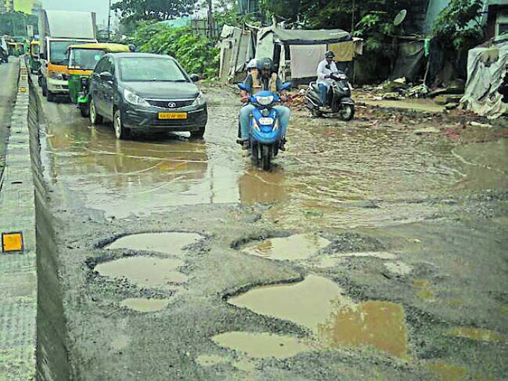 A pothole-ridden road near the Doddanekkundi flyover in Mahadevapura on Friday. DH photo.