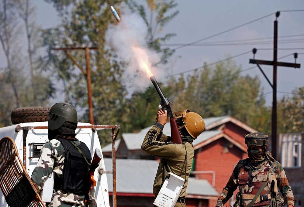 A policeman fires a teargas shell towards demonstrators during a protest ahead of the funeral of slain militant Nasrullah Mir at Hajin area of Bandipora district on Wednesday. Reuters.