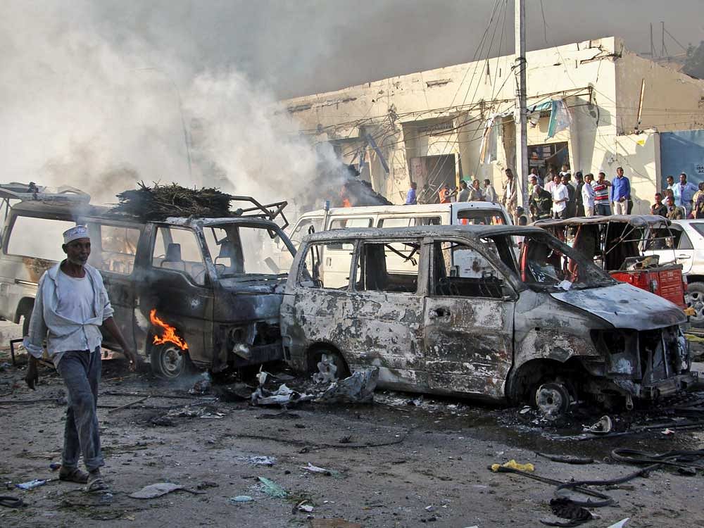 Somalis walk past the wreckage of vehicles at the scene of a blast in the capital Mogadishu, Somalia Saturday. AP/PTI Photo