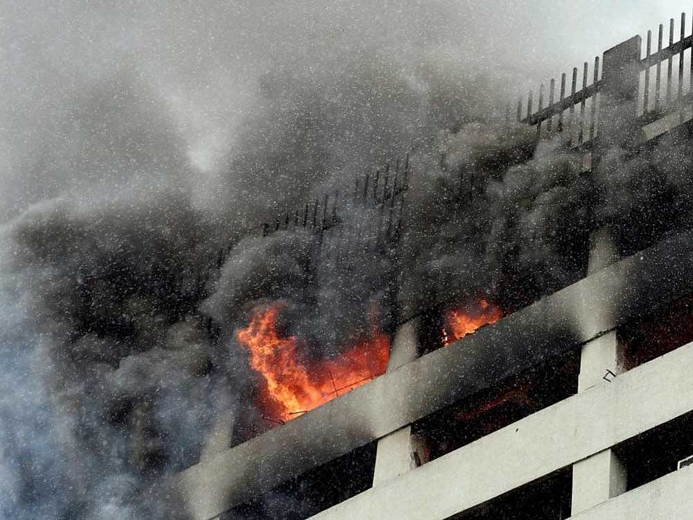 Smoke and flames comes out from the window after a high rise office building caught fire in Kolkata on Thursday. PTI