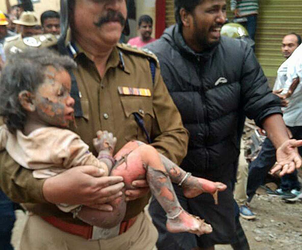 Fire personnal carrying a three year old girl Sanjana after rescuing her from the building collespe in Egipura, Bengaluru on Monday. DH Photo by Srikanta Sharma R