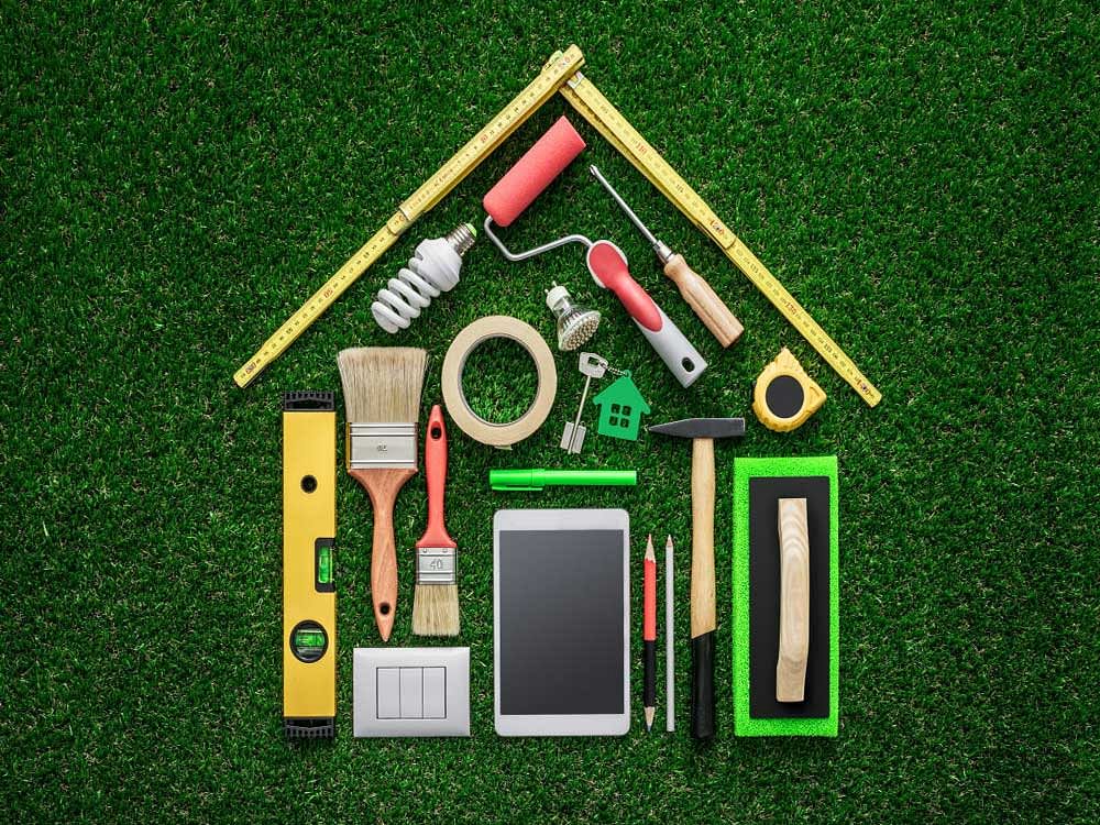 Home renovation, remodeling and DIY concept, work tools and tablet composing a house shape on the grass  renovation