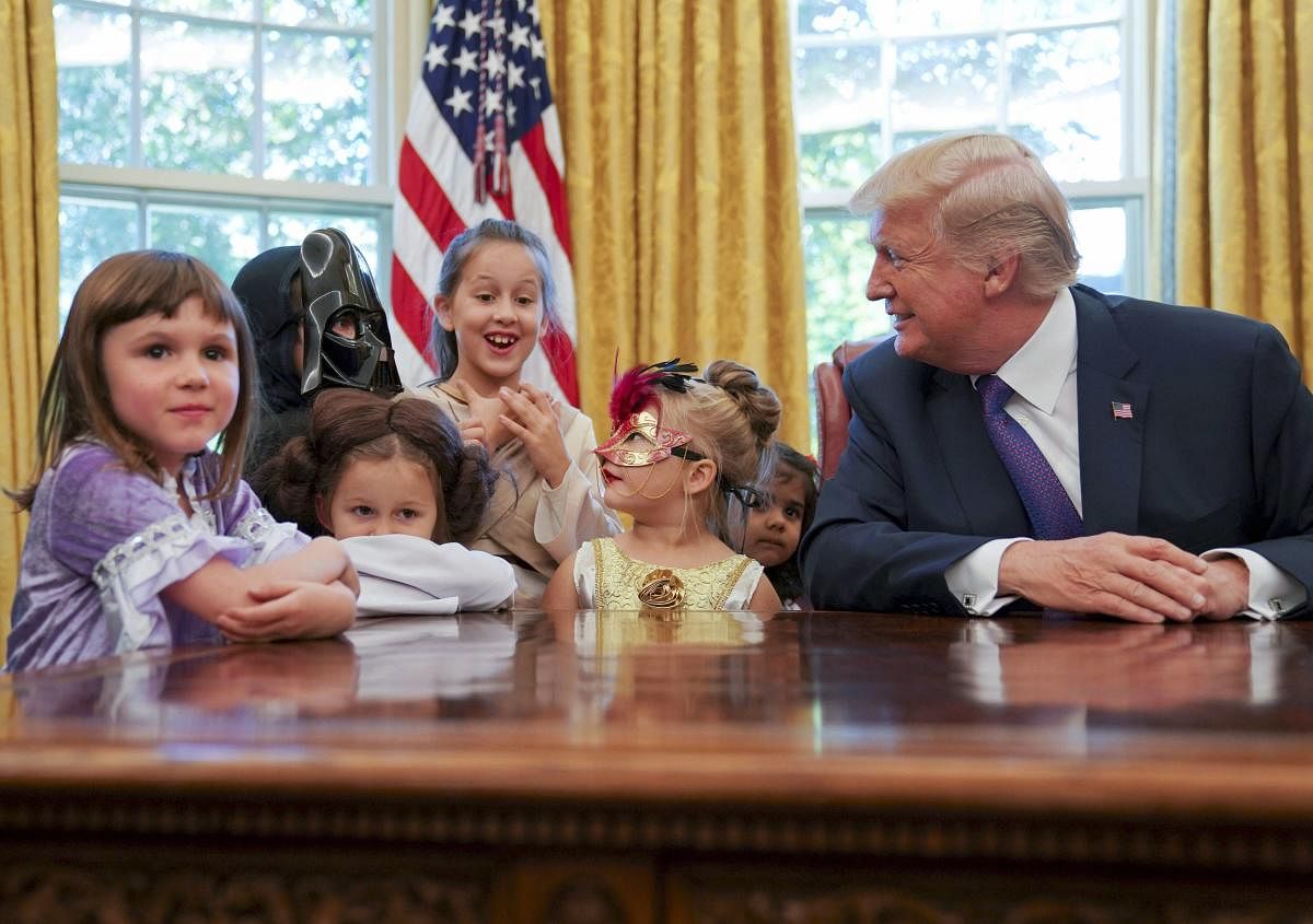 President Donald Trump meets with children dressed in their Halloween costumes in the Oval Office of the White House, Friday, Oct. 27, 2017. The White House invited the children of members of the media to visit the president and to trick-o-treat at the White House complex of the Eisenhower Executive Office building. AP/PTI