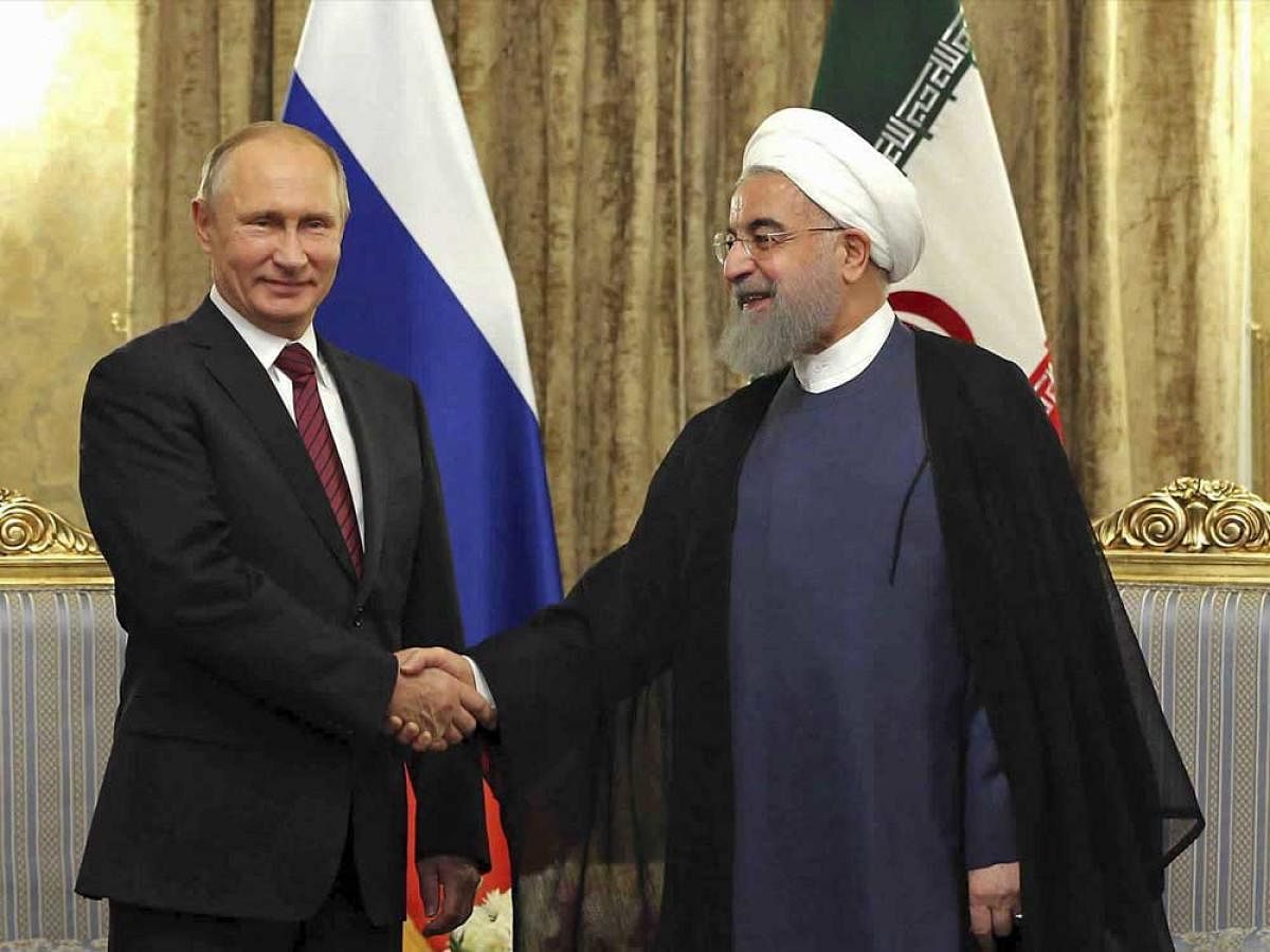 In this photo released by an official website of the office of the Iranian Presidency, Iran's President Hassan Rouhani, right, shakes hands with Russian President Vladimir Putin during their meeting at the Saadabad Palace in Tehran, Iran, Wednesday, Nov. 1, 2017. Putin arrived Wednesday for trilateral talks with Tehran and Azerbaijan, a meeting that comes as the Islamic Republic's nuclear deal is threatened by U.S. President Donald Trump's refusal to re-certify the accord.