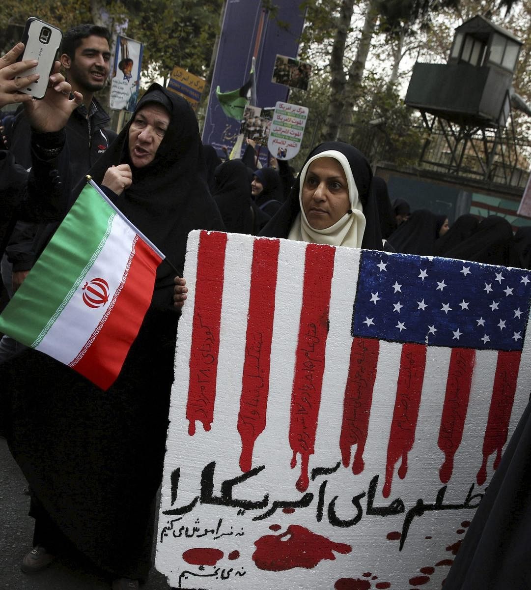 An Iranian demonstrator holds an anti-U.S. placard with writing in Persian which reads: "We'll neither forget, nor forgive cruelties of America," in an annual gathering in front of the former U.S. Embassy marking the anniversary of its 1979 takeover, in Tehran.