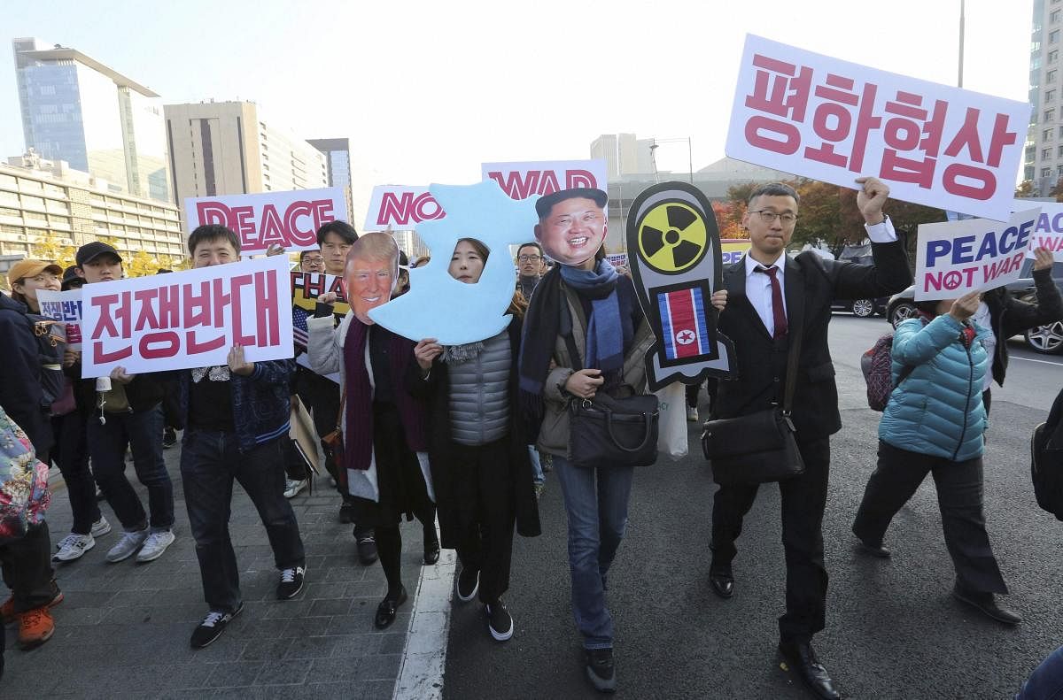 Anti-war protesters wearing masks of U.S. President Donald Trump and North Korean leader Kim Jong Un, right, march after a rally demanding peace of the Korean peninsula near U.S. Embassy in Seoul, South Korea, Sunday, Nov. 5, 2017. Trump will arrive in South Korea on Nov. 7 for a two-day visit to hold a summit with South Korean President Moon Jae-in. The placards held by the protester read: No war and peace. AP/PTI