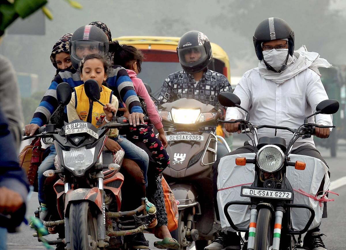 People commute amid a haze and smog, in New Delhi on Saturday. The NGT ordered that two-wheelers and women cannot be exempted from the odd-even rule. PTI photo