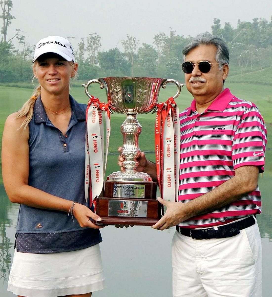 SWEET VICTORY Camille Chevalier (left) receives the Hero Women's Indian Open trophy from Pawan Munjal, CMD of Hero MotoCorp, on Sunday. PTI