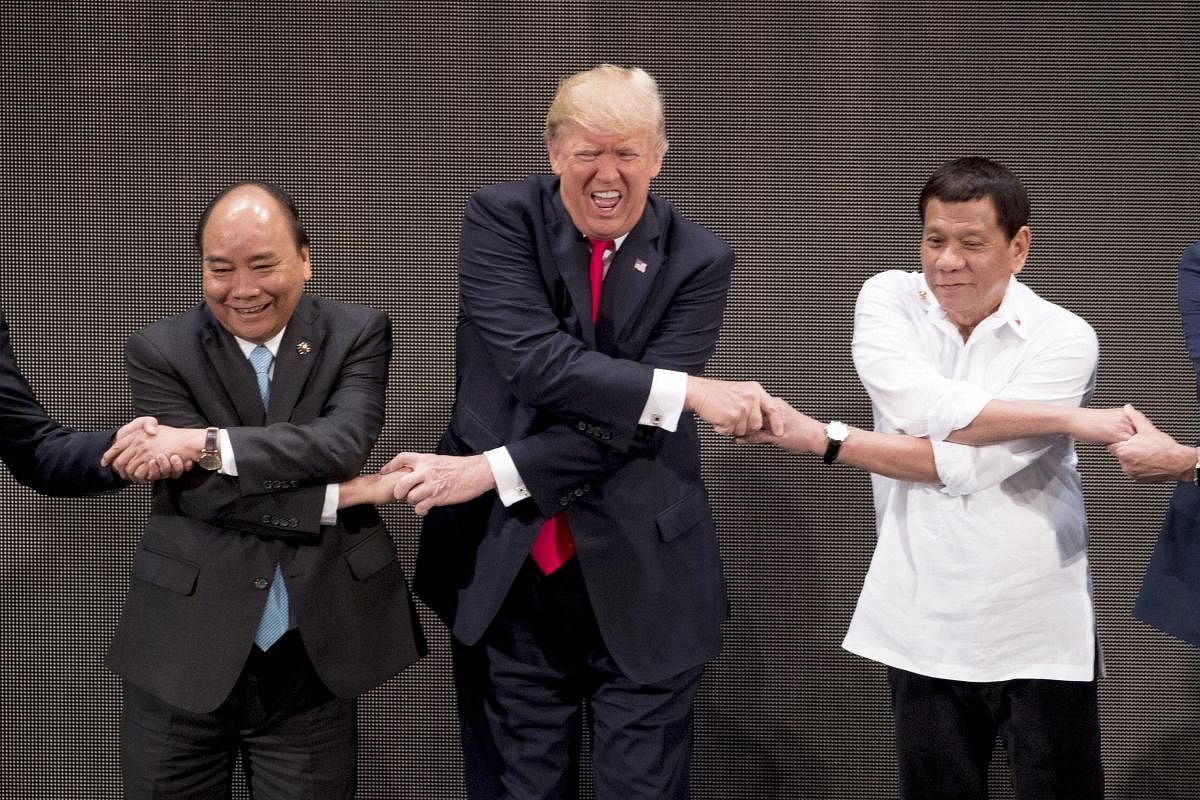 US President Donald Trump (center) reacts as he does the ASEAN-way handshake with Vietnamese Prime Minister Nguyen Xuan Phuc (left) and Philippine President Rodrigo Duterte on stage during the opening ceremony at the ASEAN Summit at the Cultural Center of the Philippines, on Monday. AP/PTI