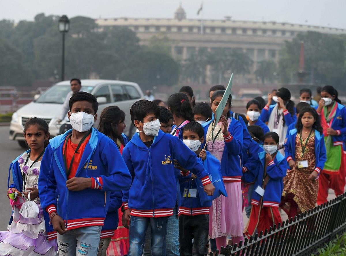 Children wearing air pollution masks attend a demonstration to spread awareness on the problem of air pollution, on Children's Day in New Delhi on Tuesday. PTI Photo
