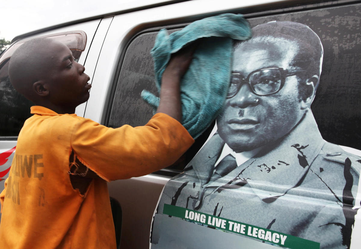Youth washes a minibus adorned with a picture of President Robert Mugabe at a bus terminus in Harare, Zimbabwe, on Wednesday. REUTERS