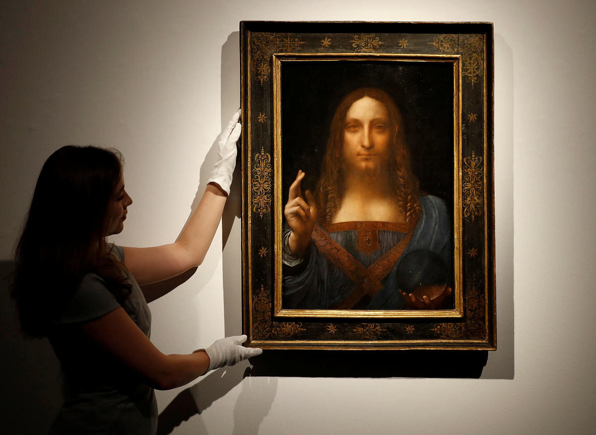 Members of Christie's staff pose for pictures next to Leonardo da Vinci's Salvator Mundi. REUTERS