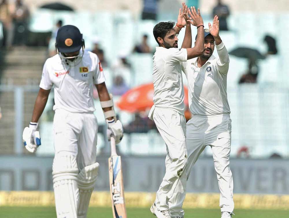 Bhuvneshwar Kumar celebrates with his teammate C Pujara after he dismissed Sri Lankan batsman S Samarawickrama (L) during the third day of 1st Test match against Sri lanka. PTI photo.
