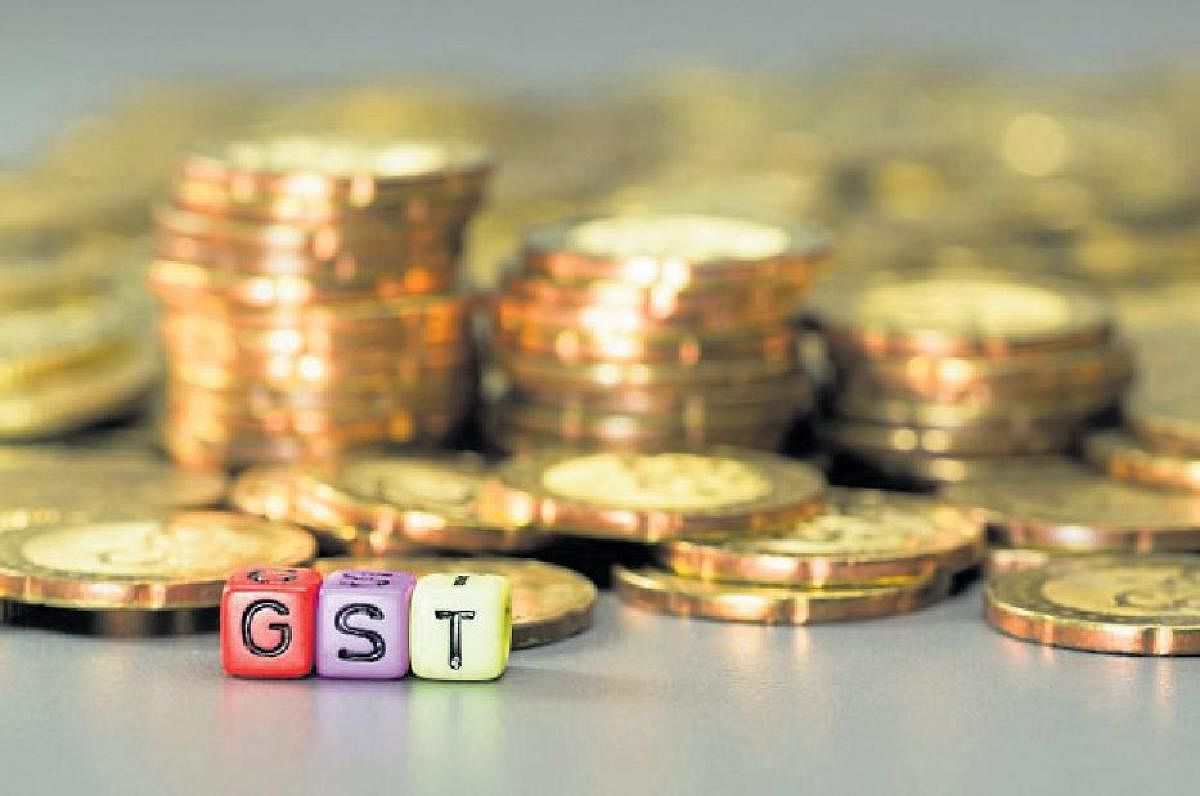 GST or Good and Services Tax word written on colorful dice and gold coins in the background