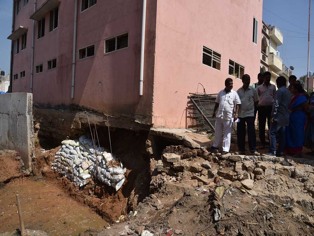 The residents gather near the building of Government Higher Primary School Manorayanapalya, Hebbal, where the BBMP has taken up work to erect retaining wall to the stormwater drain. DH pHOTO