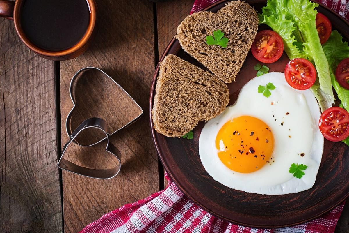 Breakfast on Valentine's Day - fried eggs and bread in the shape of a heart and fresh vegetables. Top viewEggs
