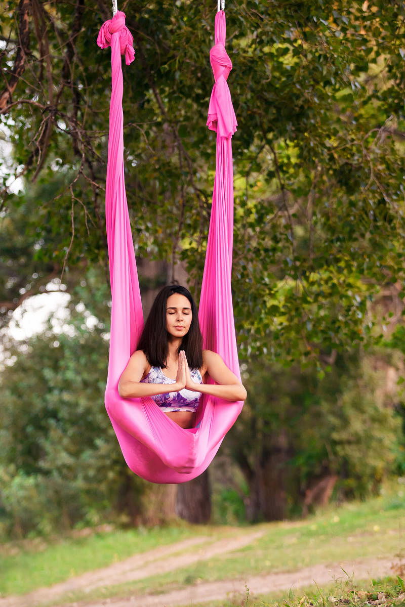 Aerial antigravity yoga. Young healthy women doing lotus pose on silk hammock at natureAerial yoga