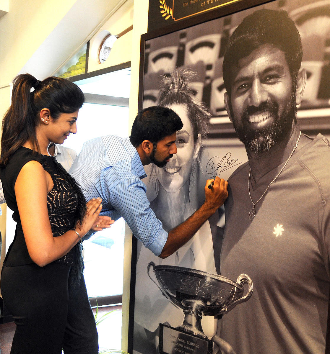 Rohan Bopanna signing the photograph depicting his French Open mixed doubles triumph with Gabriela Dabrowski at the KSLTA stadium on Friday. Bopanna's wife Supriya is at left. DH Photo