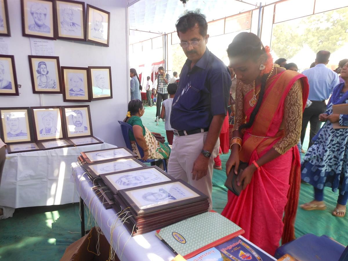 Visitors take a look at the art works of U G Mohan Kumar Aradhya displayed during the 83rd Akhila Bharatha Kannada Sahitya Sammelana in Mysuru on Friday.