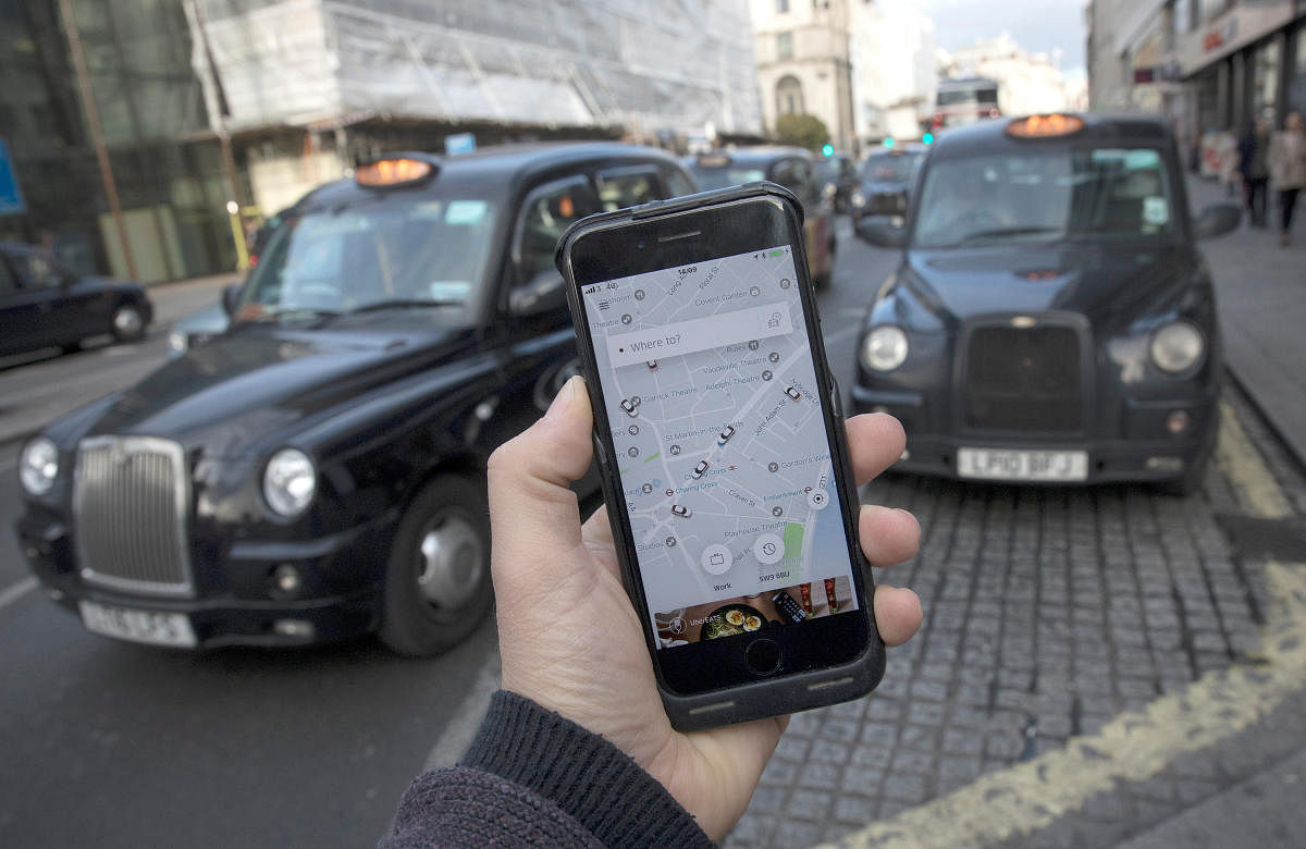 A photo illustration shows the Uber app on a mobile telephone, as it is held up for a posed photograph, with London Taxis in the background, in London, Britain November 10, 2017. REUTERS/Simon Dawson