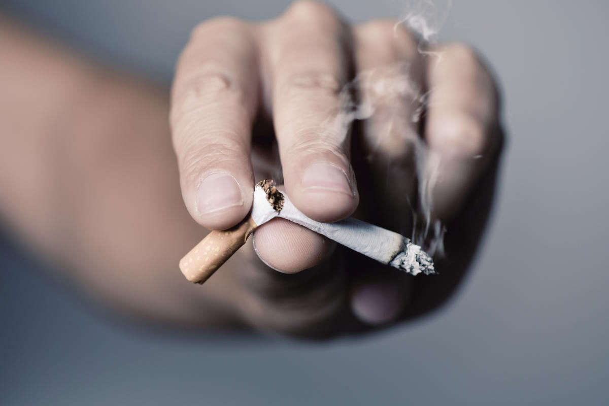 closeup of the hand of a young caucasian man breaking a lit cigarette with his fingersLung cancer