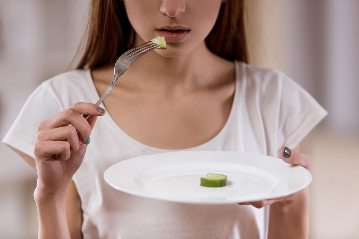 Thin girl with an empty plate standing in the center of the room closeup, malnutrition harms health.Menopause