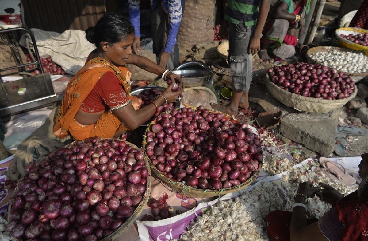 An Indian vegetable seller sorts onions at a roadside market in Siliguri on November 28, 2017. The price of onions have risen sharply in the past few months, quadrupling to as much as 65 rupees a kilogram in some parts of the country and turning the vegetable into an unaffordable luxury for the poor. / AFP PHOTO / DIPTENDU DUTTA