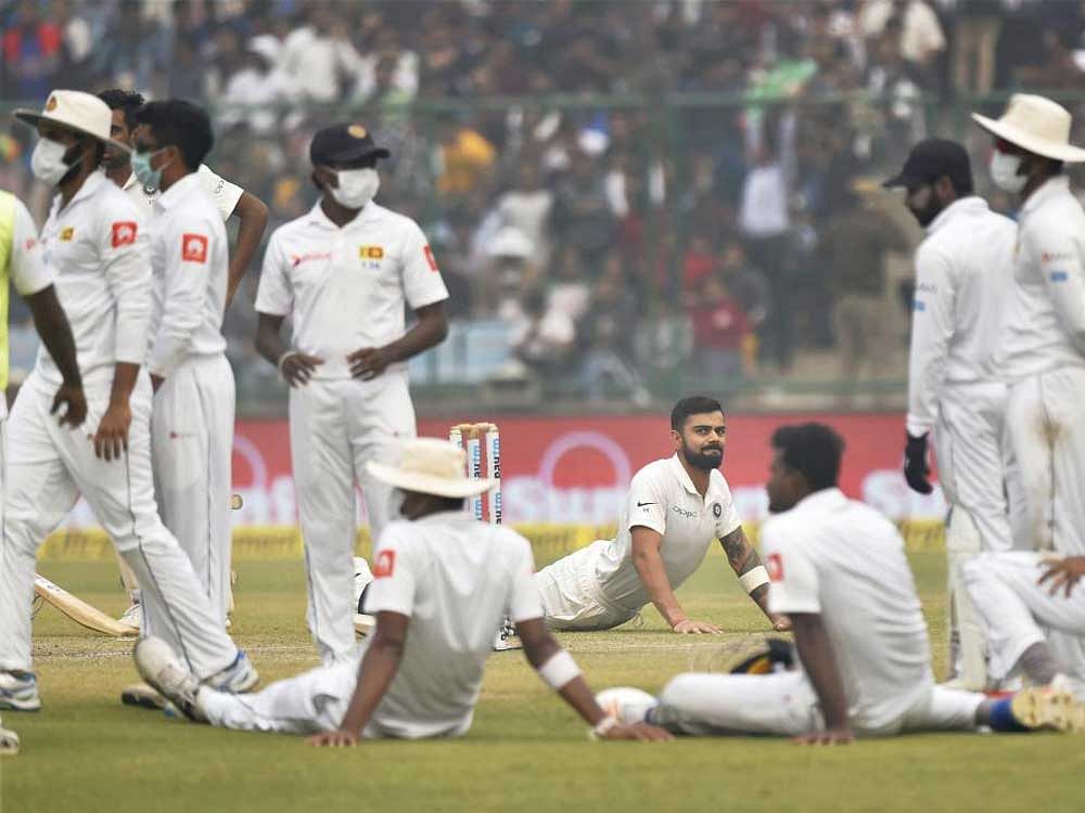 Sri Lankan players wear anti-pollution masks on the field, as the air quality deteriorates during the second day of their third test cricket match against India in New Delhi on Sunday. India's Virat Kohli (stretching) is also seen. PTI Photo