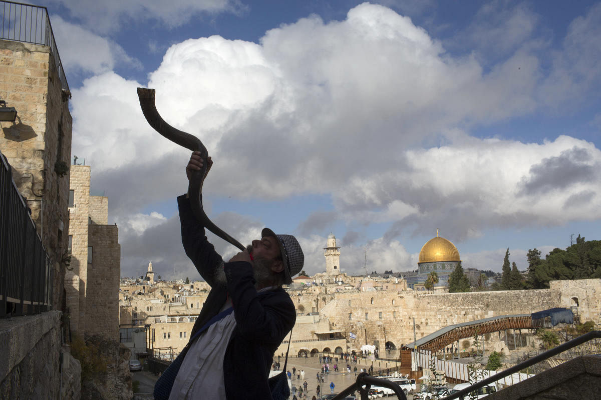 A Jewish man blows a shofar with the Dome of the Rock in the distance, in Jerusalem, Dec. 6, 2017.President Trump plans to name Jerusalem as the capital of Israel on Wednesday, upending nearly seven decades of American foreign policy. (Uriel Sinai/The New York Times)