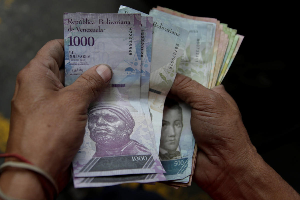 A worker counts Venezuelan bolivar notes at a gas station in Caracas. Reuters File