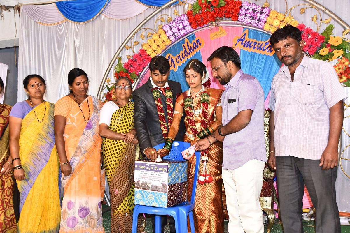 Giridhar and Amrutha place their 'Ayer' money to the donation box for the army welfare fund, during their wedding at Divategalli in Hubballi on Monday.