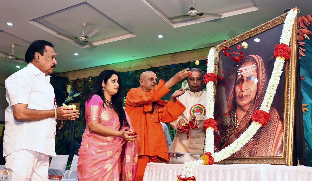 Sa Ra Govindu, Roopa Iyer and Sri Panditaradhya Shivacharya Swamiji pay floral tributes to the portrait of Guravva Shivalingappa Horatti, at the 'Avva' award presentation ceremony in Hubballi on Saturday. MLC Basavaraj Horatti looks on.