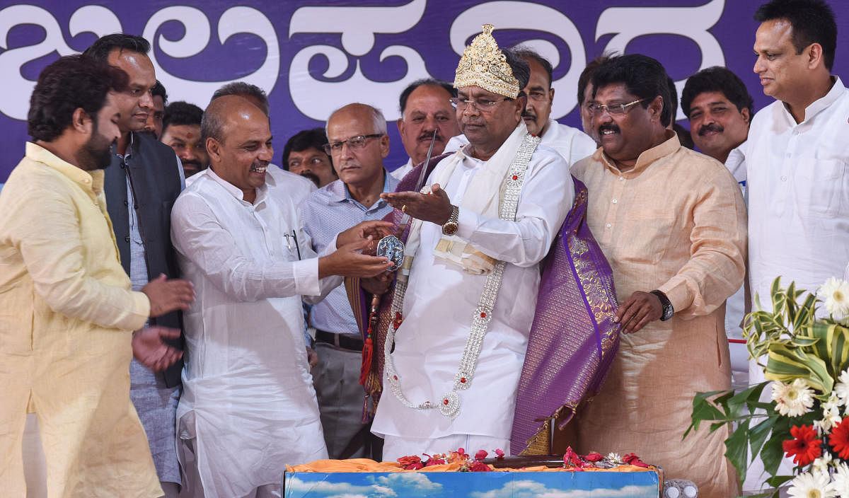 Chief MinisterSiddaramaiah is presented with a gold-coated crown, a garland made of silver and a silver sword during a programme in Afzalpur in Kalaburagi district on Saturday. Ministers Priyank Kharge and Sharanprakash Patil and MLAs Malikayya Guttedar and Ajay Singh are seen. DH Photo.