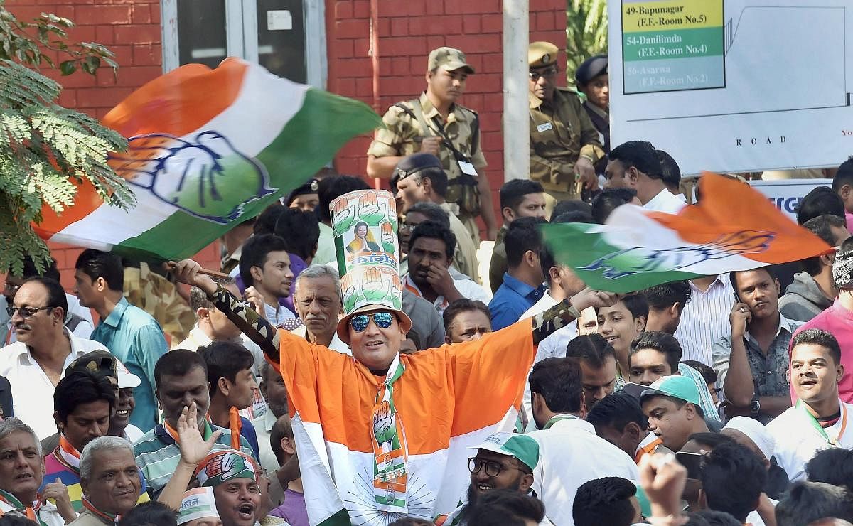 Congress supporters celebrate a candidate's win outside a counting centre in Ahmedabad on Monday. PTI