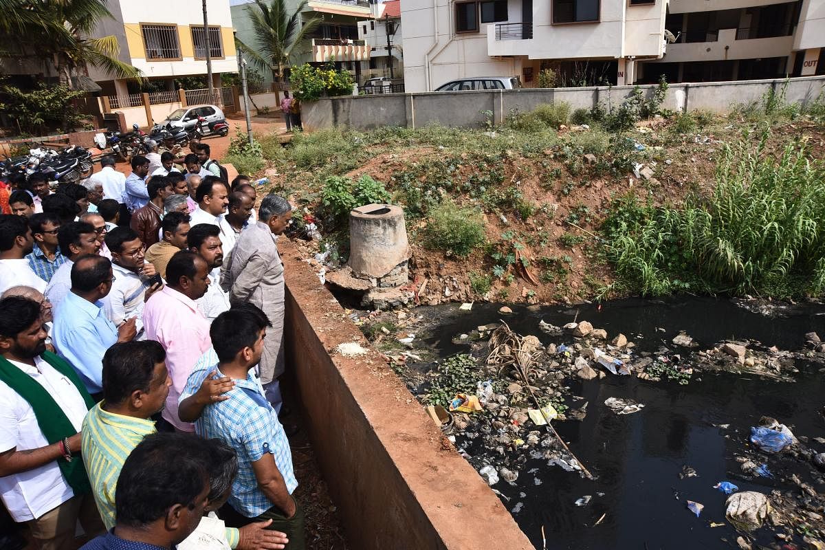 MLC Basavaraj Horatti and others look at the Nala where sewage water is flowing, at Vidyanagar area in Hubballi on Monday.