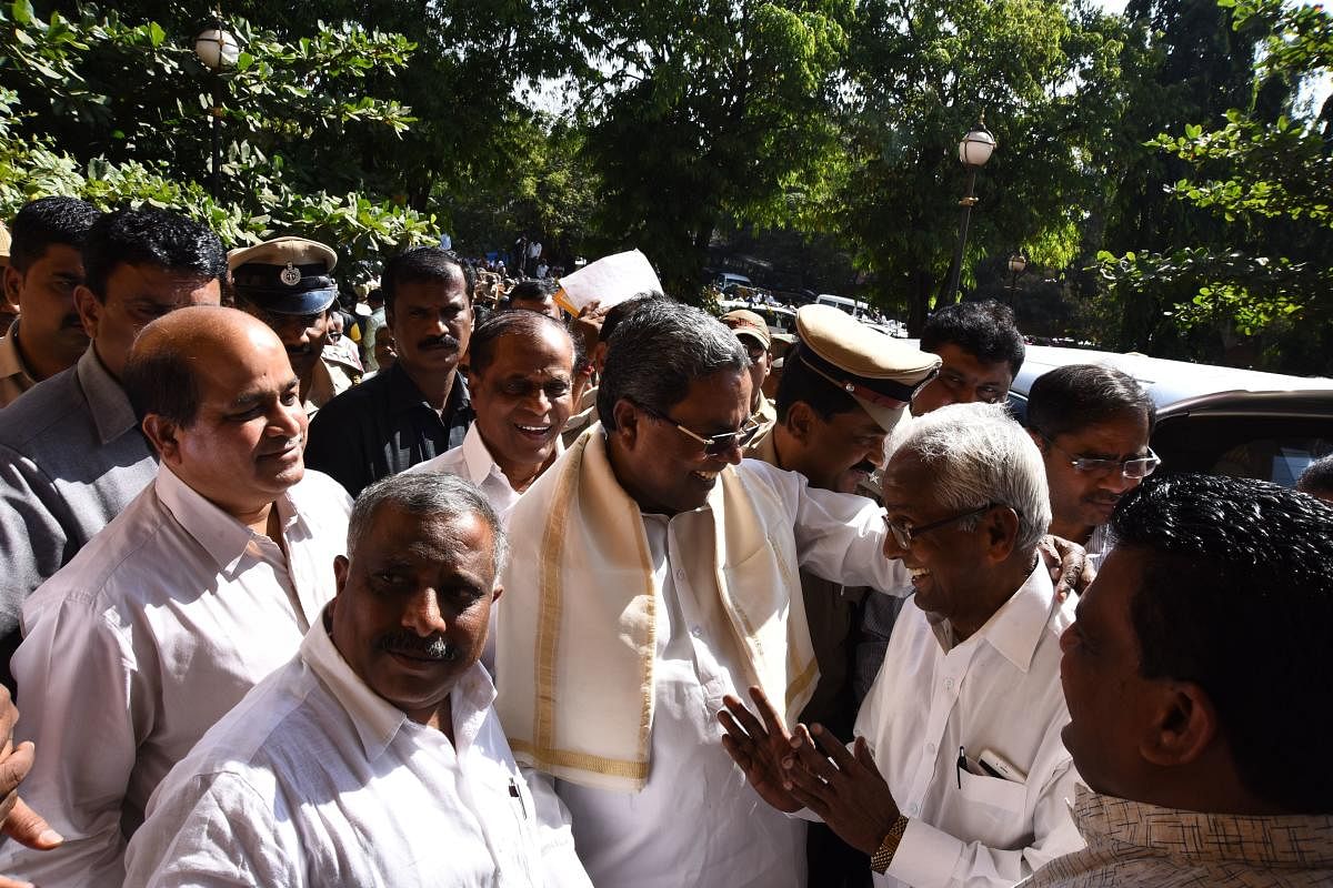 Chief Minister Siddaramaiah interacts with a leader, at the circuit house premises in Hubballi on Monday.