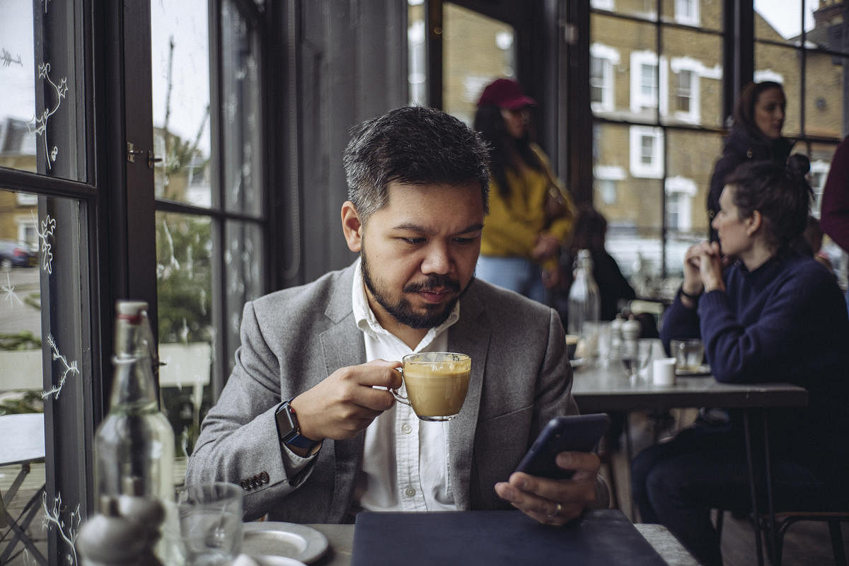 Michael de la Merced, a DealBook reporter for The New York Times, checks his iPhone X at a cafe in London, Dec. 23, 2017. Calling the new model a remarkable evolution of the smartphone, de la Merced said it is by far his favorite tool for his job. (Tom Jamieson/The New York Times)