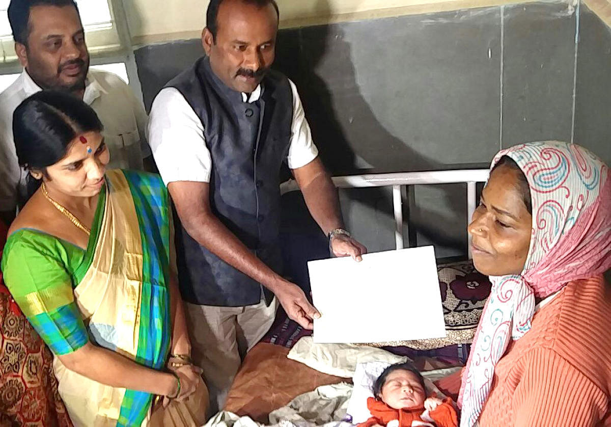 Mayor Sampath Raj handing over a cheque of Rs 5 lakh to Pushpa, who the mother of a new born baby on New Year's eve to time in BBMP hospital to baby's mother in Bengaluru on Monday. Also seen deputy mayor Padmavati narasimha Murty.