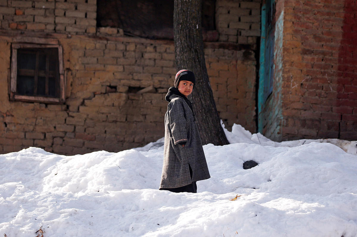 A boy stands on snow outside his home on a cold winter morning at Haripora village, South Kashmir, on Wednesday. REUTERS