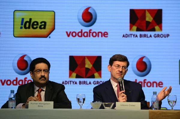 Vodafone Group CEO Vittorio Colao (R) speaks as the chairman of India's Aditya Birla Group Kumar Mangalam Birla watches during a news conference in Mumbai on March 20, 2017. British mobile phone giant Vodafone's Indian unit will merge with Idea Cellular to create India's largest telecoms operator, the firms said Monday, as they combine to fight the rise of Reliance Jio. / AFP PHOTO / PUNIT PARANJPE