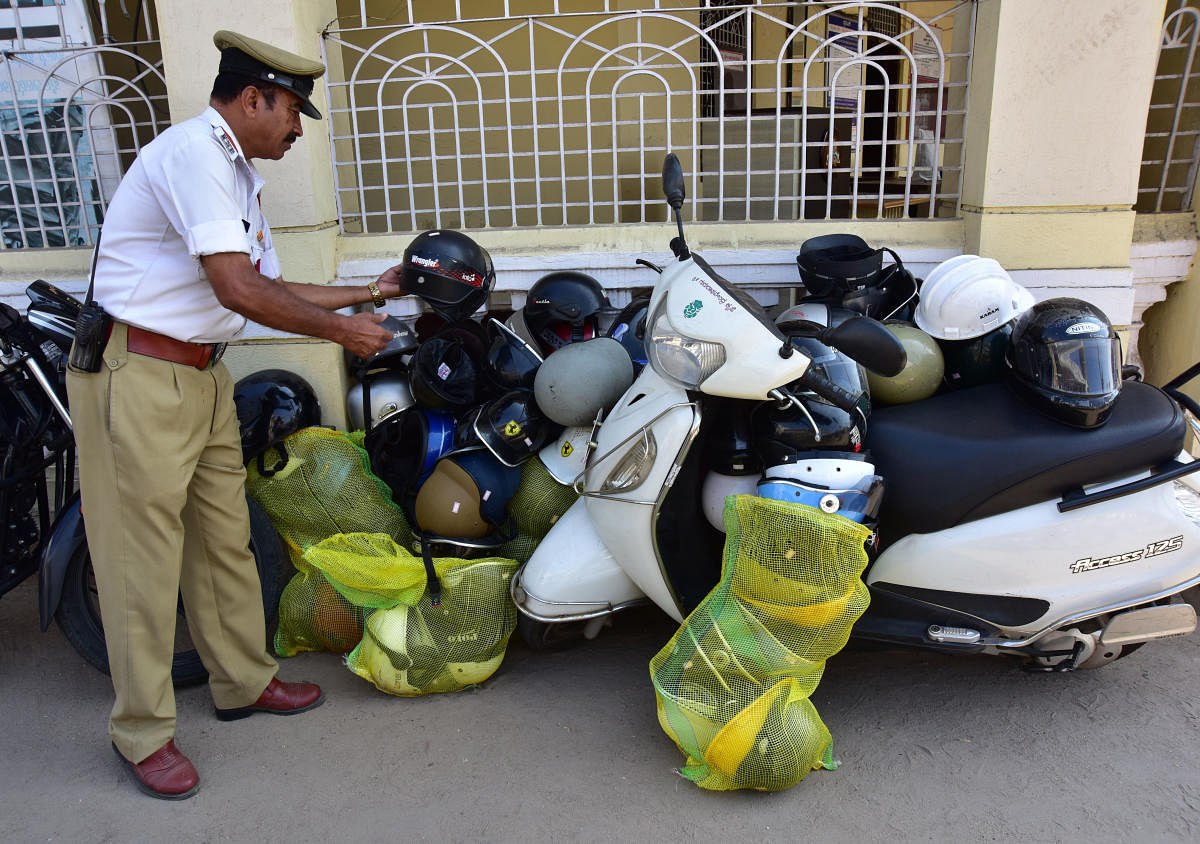 Police personnel keeps the helmet which they collected during drive against half non ISI mark helmet, at Ashoka Road in Mysuru on Tuesday January 02, 2018- PHOTO / IRSHAD MAHAMMAD