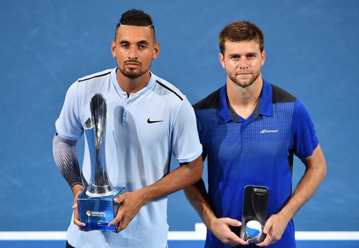 Nick Kyrgios of Australia (L) holds the trophy after beating Ryan Harrison of the US (R) to win the men's singles final at the Brisbane International tennis tournament at the Pat Rafter Arena in Brisbane on January 7, 2018. / AFP PHOTO / SAEED KHAN / IMAGE RESTRICTED TO EDITORIAL USE - STRICTLY NO COMMERCIAL USE