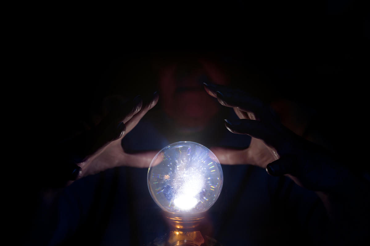 A seer working over a glowing crystal ball, foretelling the future.